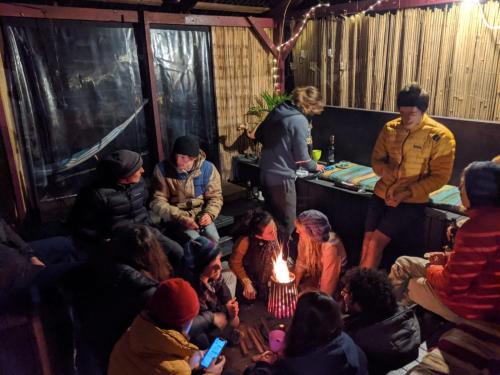 a group of people sitting in a room with a fire at Flying Fox Backpackers in Katoomba