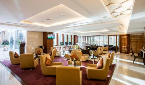 a hotel lobby with couches and tables and chairs at The Grand Fourwings Convention Hotel Bangkok in Bangkok