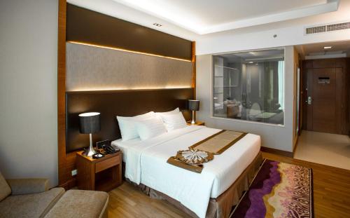 a hotel room with a large bed and a couch at The Grand Fourwings Convention Hotel Bangkok in Bangkok