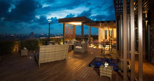 a deck with chairs and tables on a building at night at The Grand Fourwings Convention Hotel Bangkok in Bangkok