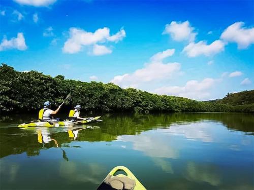 two people in kayaks on a river with trees at irregular INN Nakijin in Nakijin