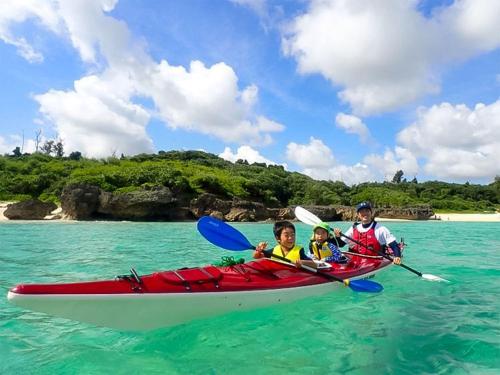 three people in a red kayak in the water at irregular INN Nakijin in Nakijin