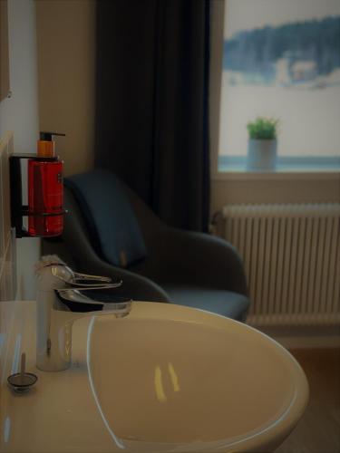 a white sink in a room with a chair and a window at Sjövillan Bed & Breakfast in Sandöverken