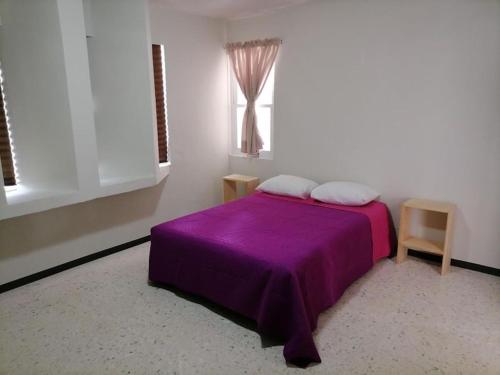 1 dormitorio con cama morada y ventana en Amplio Departamento, Seguridad, Ubicacion Pb, en Querétaro