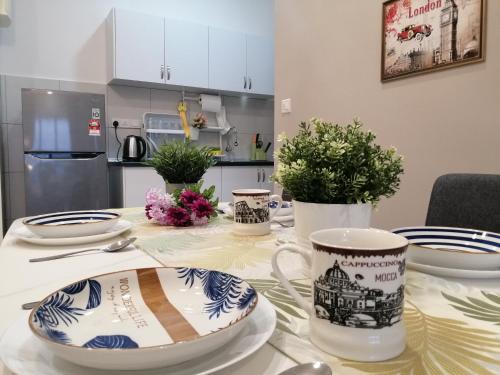 a table with plates and cups on top of it at Astetica Residences @ Seri Kembangan in Seri Kembangan