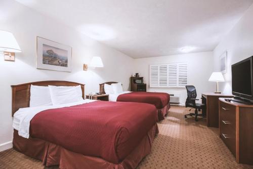 a hotel room with two beds and a flat screen tv at Sky-Palace Inn & Suites McCook in McCook