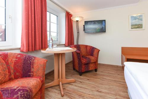 a living room with a table and a chair at Hotel Garni Benser Watt in Bensersiel