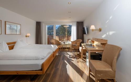 a hotel room with a bed and a table and chairs at Sunstar Hotel Arosa in Arosa