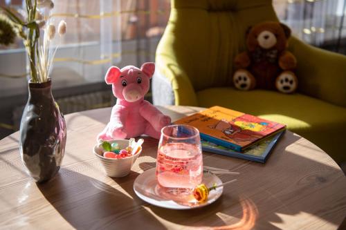 a pink teddy bear sitting on a table with a drink at Sunstar Hotel Arosa in Arosa