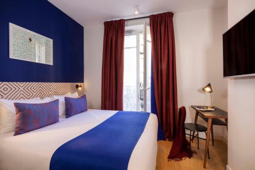 Un dormitorio con una cama azul y blanca y un escritorio en Paris Art Hotel Quartier Latin by Malone, en París