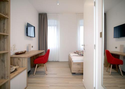 um quarto com uma cama, uma secretária e cadeiras vermelhas em Pansion Legrađanka em Legrad