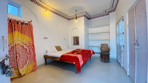 a bedroom with a bed with a red blanket at Sai Baba Haveli in Pushkar