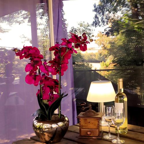a table with a vase with red flowers and a bottle of wine at Camping maeva Escapades Le Domaine Aramis in Marsan