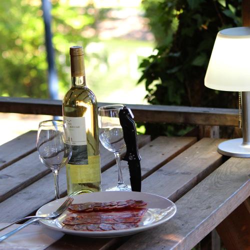 a bottle of wine and a plate of bacon and wine glasses at Camping maeva Escapades Le Domaine Aramis in Marsan