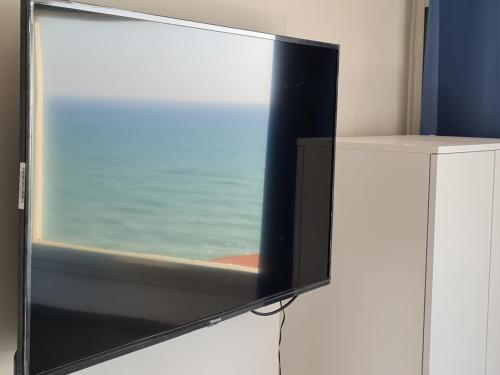 una TV a schermo piatto seduta sopra un armadio bianco di שיין רויאל חוף צאנז סוויטות פרטיות עם מרפסת וג'קוזי לקהל הדתי חרדי דקה ממלון גלי צאנז a Netanya