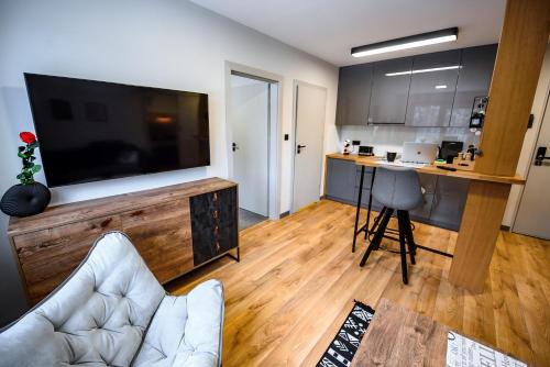 a living room with a flat screen tv and a kitchen at Wójcik SPA - Krynica Zdrój in Krynica Zdrój