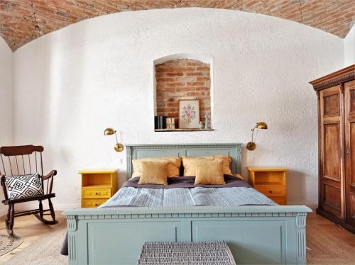 a bedroom with a blue bed and a brick wall at 400 Éves Ház Vendégház in Kőszegszerdahely