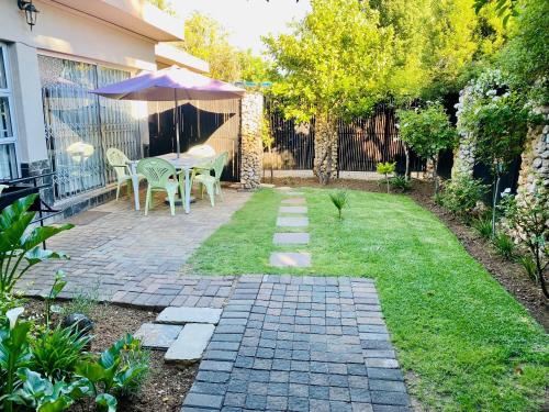 a patio with a table and an umbrella in a yard at Cottonwood Guesthouse Oasis in Bloemfontein
