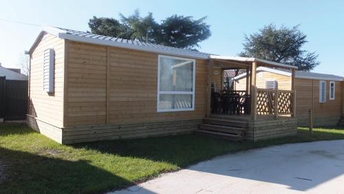 a large wooden cabin with a deck on the grass at CAMPING ONLYCAMP DU MOULIN in Clisson