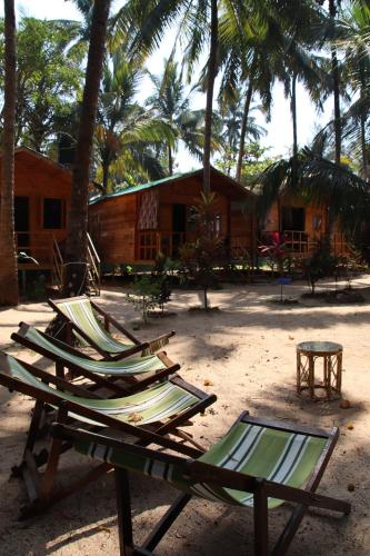 a group of chaise lounges on a beach with a resort at Cilantro Agonda in Agonda