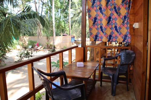 a porch with a wooden table and chairs and a quilt at Cilantro Agonda in Agonda