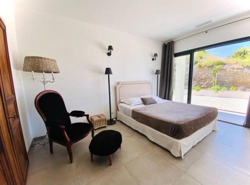 1 dormitorio con 1 cama, 1 silla y 1 ventana en Villa prestige au bord de l'eau- Pietracorbara, en Pietracorbara