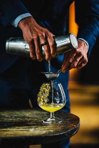 a person is pouring alcohol into a wine glass at The Dylan Amsterdam - The Leading Hotels of the World in Amsterdam