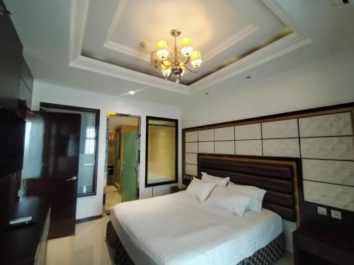 a bedroom with a large white bed with a chandelier at Prime Asia Hotel in Angeles