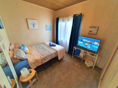 a bedroom with a bed and a flat screen tv at WOODY Pt - AMAZING 1970's SHARE HOUSE BY THE SEA-4 rooms available! in Woody Point