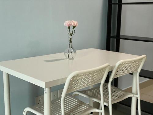 Biały stół z 2 krzesłami i waza z kwiatami w obiekcie CQ28-SELF CHECK IN- Wifi- Netflix- Parking-New, 2017 w mieście Cyberjaya