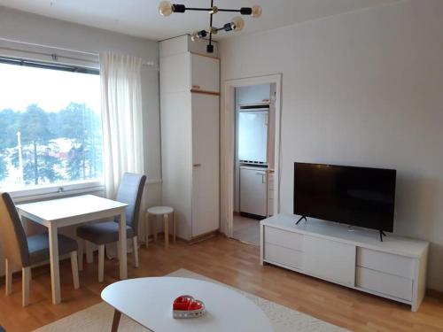 uma sala de estar com uma televisão de ecrã plano e uma mesa em Viihtyisä yksiö Oulun Tuirassa em Oulu