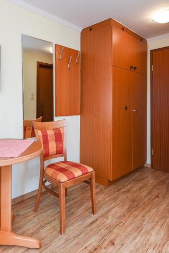a room with a table and a chair and a cabinet at Hotel Garni Benser Watt in Bensersiel