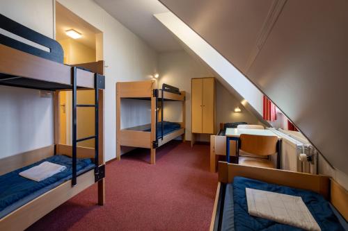a room with three bunk beds and a staircase at Stayokay Hostel Arnhem in Arnhem