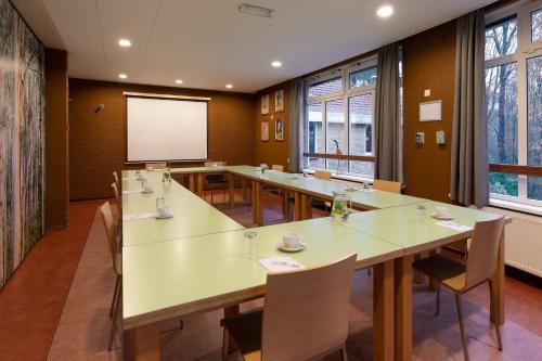 a conference room with tables and chairs and a screen at Stayokay Hostel Arnhem in Arnhem