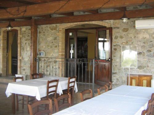 un comedor con mesas blancas y sillas de madera en Agriturismo San Fele, en Cerchiara di Calabria