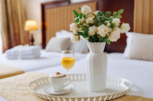 a table with a vase of flowers and a plate with a glass of wine at Garni Hotel Planeta Inn in Novi Sad