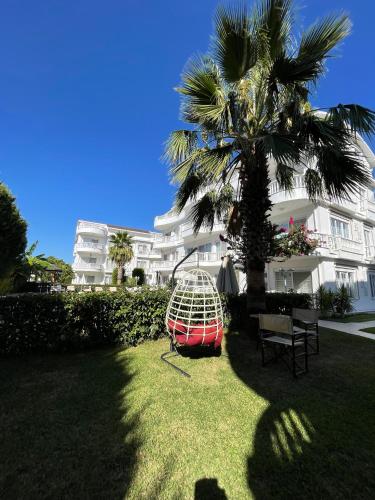 a palm tree and a hammock in front of a building at BELKA GOLF RESİDENCE Deluxe apt Poolside BELEK in Belek
