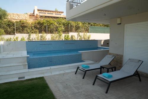 a patio with two chairs and a swimming pool at Luxury heated pool Villa in Lagonissi