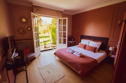 a bedroom with a large bed and a large window at Les jardins de Beaumont in Hem