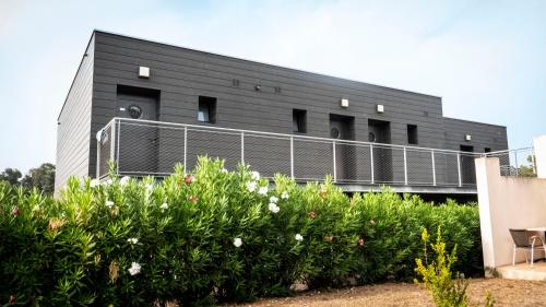a black building with some flowers in front of it at Hotel Olmuccio in Sainte-Lucie de Porto-Vecchio