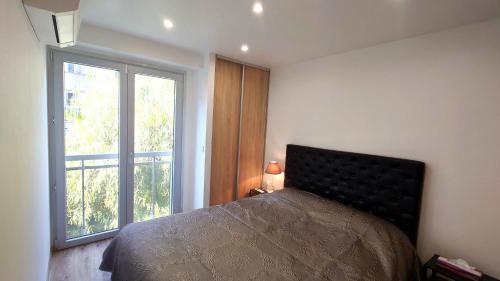 une chambre avec un lit et une grande fenêtre dans l'établissement Magnifique appartement à 10mn du Palais, à Cannes