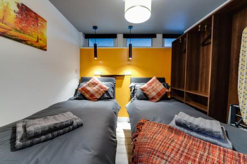 two twin beds in a room with yellow walls at 1 Bedroom Swinley Apartment l Free Parking l Wigan Royal Infirmary l Haigh Hall l Central Location in Wigan