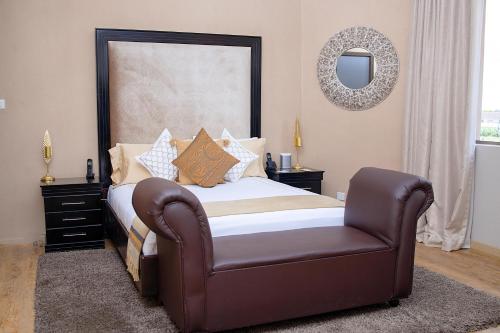 a bedroom with a bed with a chair and a mirror at Masawara Urban Retreat in Harare