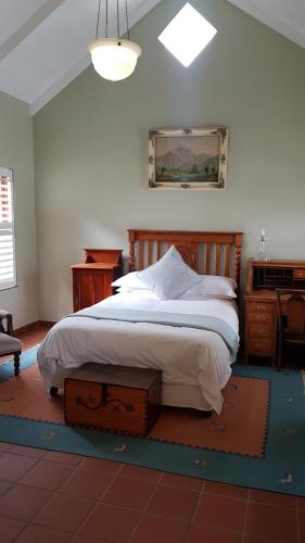 a bedroom with a bed with a wooden headboard and a desk at Burkleigh House in Johannesburg