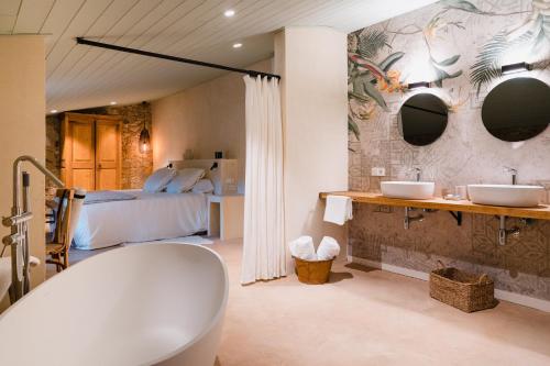 a bathroom with two sinks and a bed and a tub at Mas Rauric in Llagostera