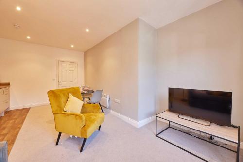 a living room with a yellow chair and a flat screen tv at Wearmouth boutique apartment in Sunderland