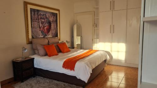 a bedroom with a bed with orange pillows on it at Kayalako on 4th Avenue in Benoni