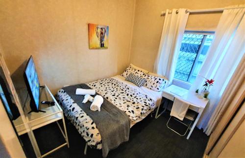 a bedroom with a bed and a tv and a window at WOODY Pt - AMAZING 1970's SHARE HOUSE BY THE SEA-4 rooms available! in Woody Point