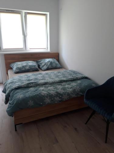 a bed in a bedroom with two windows at Apartament Nova in Dębina
