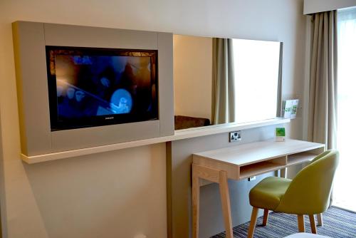a room with a tv and a desk and a chair at Holiday Inn Northampton West M1 Junc 16, an IHG Hotel in Northampton